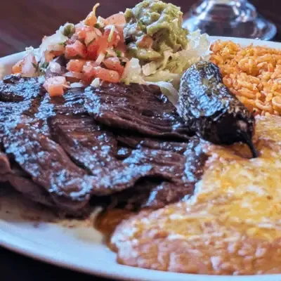 Carne asada with rice, beans, and a roasted pepper